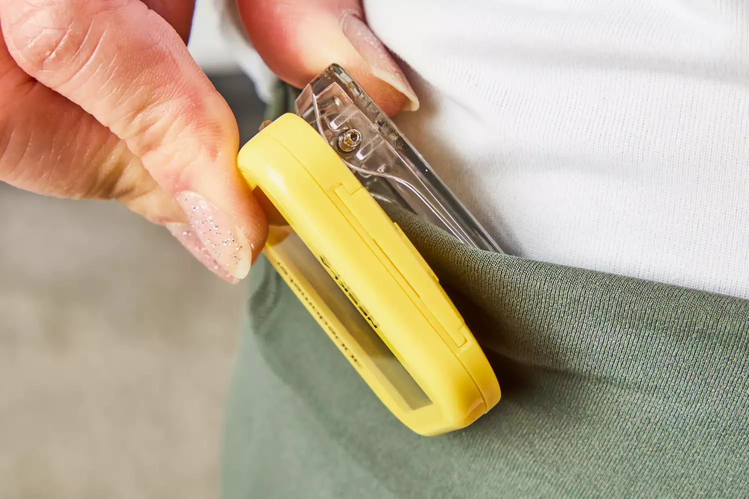 A person clips the NESKLA 3D Pedometer with Large Digital Display to their waistband