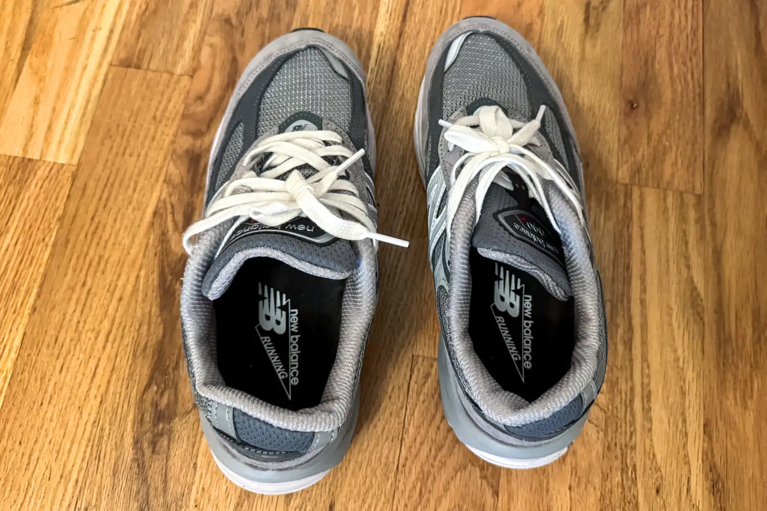 A pair of New Balance Women's Made in USA 990v6 Sneakers on a wooden floor