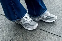 A person wears the New Balance Women's Made in USA 990v6 Sneakers with jeans