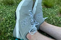 A side view of a person wearing a pair of New Balance Men's 608v5 Cross Trainer Shoes in grass