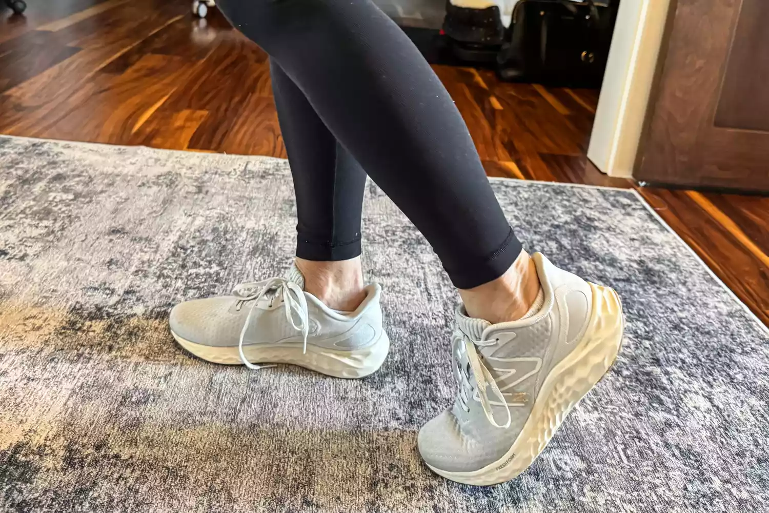 A person's feet posed on a rug while wearing the New Balance Women's Fresh Foam Arishi v4