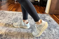 A person's feet posed on a rug while wearing the New Balance Women's Fresh Foam Arishi v4