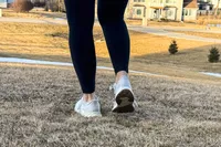 A person's legs from the back whilw they wear the New Balance Women's Fresh Foam Arishi v4 in grass