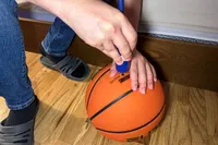 A person pumps air into the Nike Elite Championship Basketball