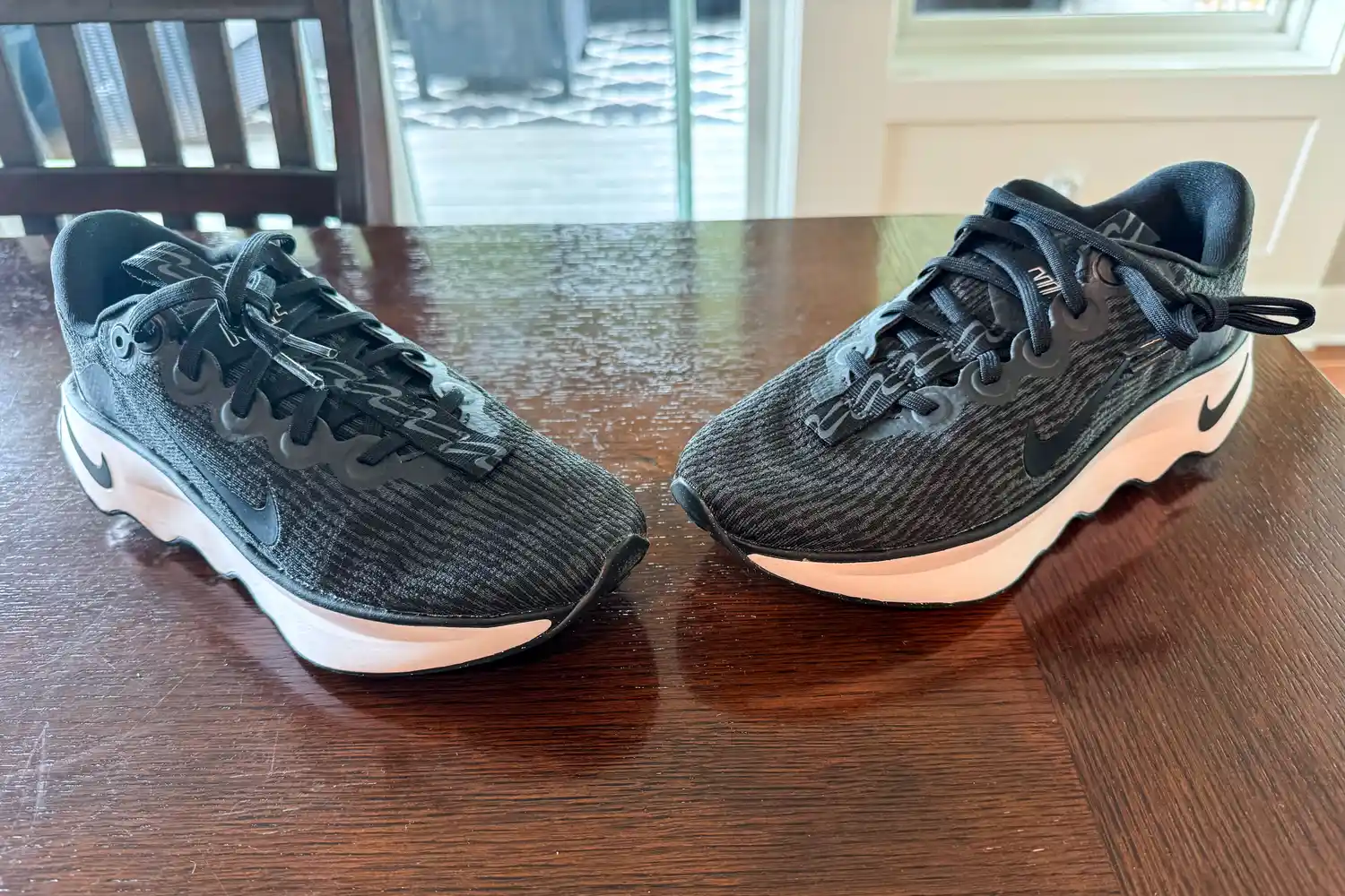 A pair of Nike Motiva Women's Walking Shoes on a wooden table