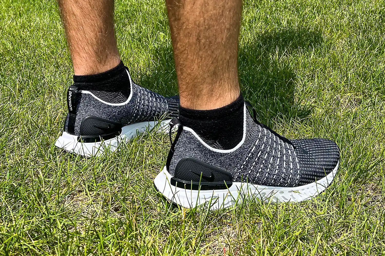 A side view of a person wearing the Nike React Phantom Run 2 Men's Road Running Shoes in grass