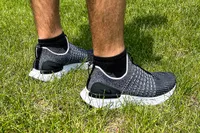 A side view of a person wearing the Nike React Phantom Run 2 Men's Road Running Shoes in grass