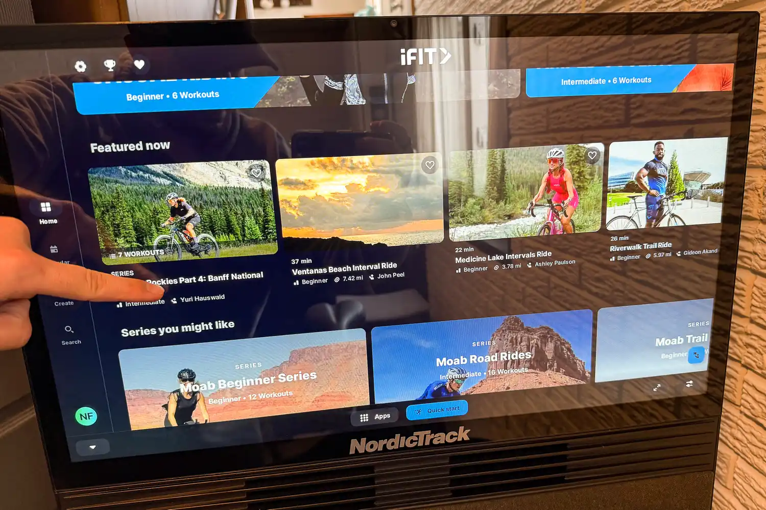 A person presses the touchscreen on the NordicTrack X24 Bike