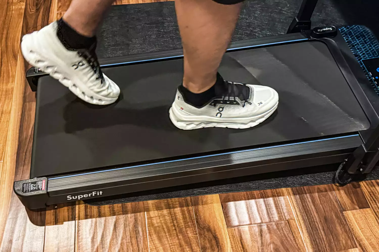 A person walks on a treadmill while wearing the On Men's Cloudtilt Walking Shoes