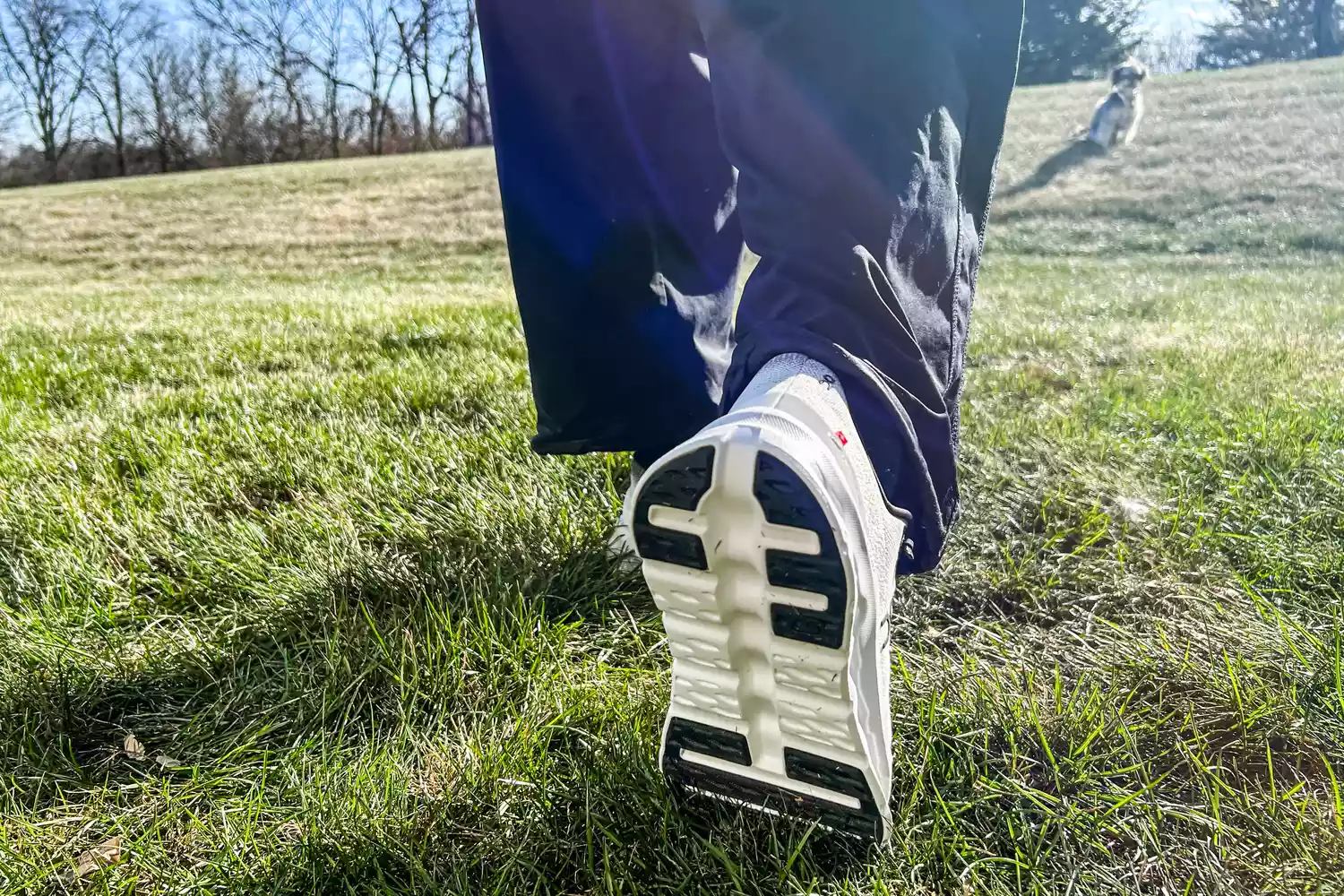 A person walks outside while wearing the On Men's Cloudtilt Walking Shoes