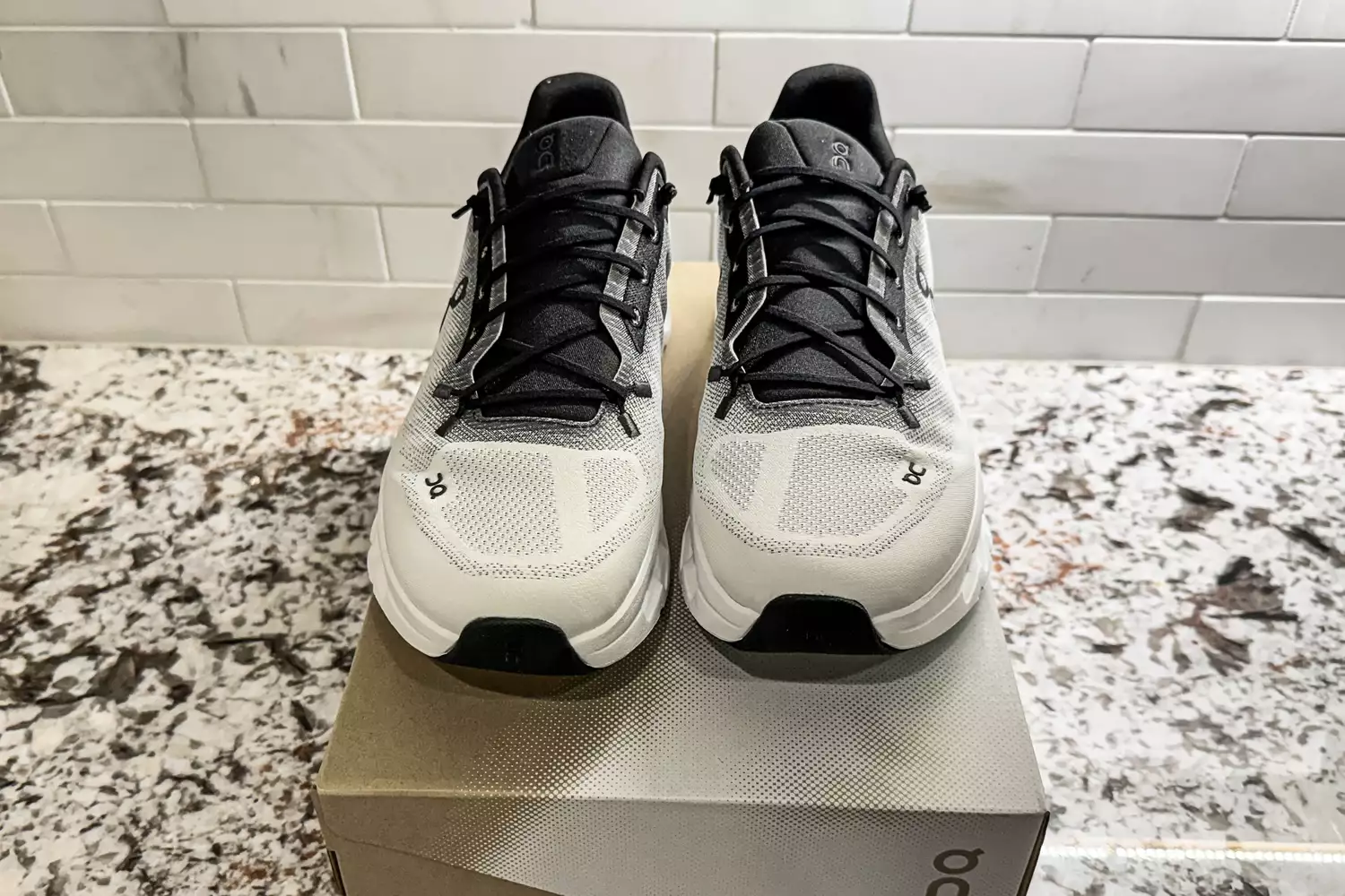 A front view of a pair of On Men's Cloudtilt Walking Shoes on a shoebox