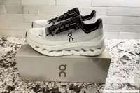 A pair of On Men's Cloudtilt Walking Shoes on a branded shoebox