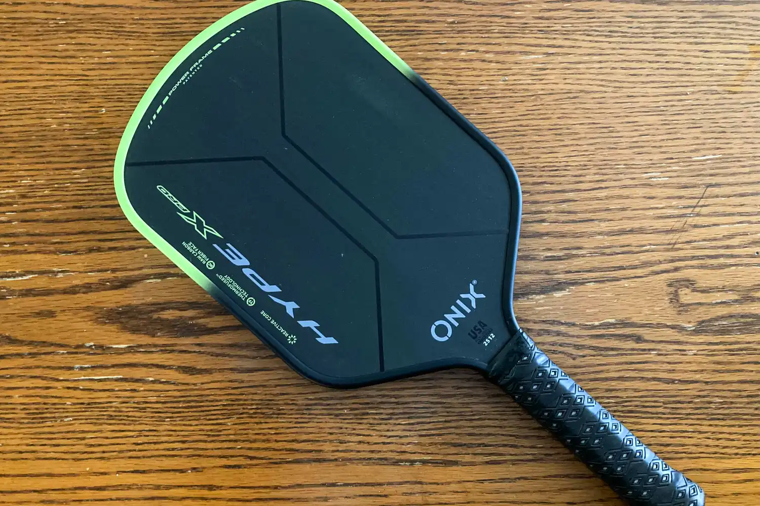 The Onix Hype X Pro Raw Carbon Pickleball Paddle on a wooden table
