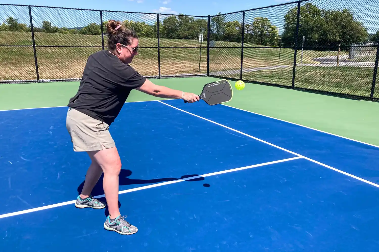 A person hits a ball with the Onix Hype X Pro Raw Carbon Pickleball Paddle