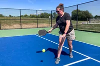 A person hits a pickleball with the Onix Hype X Pro Raw Carbon Pickleball Paddle