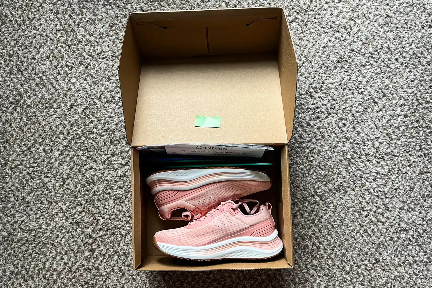 A pair of Orthofeet Women's Relay Sneakers in a cardboard box on a carpeted floor