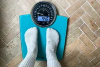 A person stands on the Ozeri Rev 400 lbs Bathroom Scale in socks