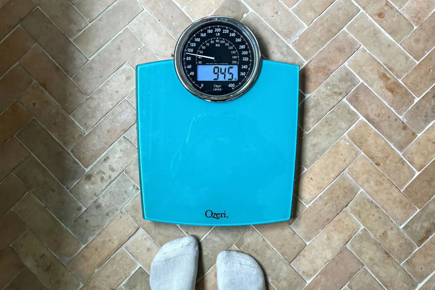 The Ozeri Rev 400 lbs Bathroom Scale on a brick floor