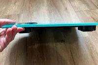 A person holds up the Ozeri Rev 400 lbs Bathroom Scale to show the thickness of the scale