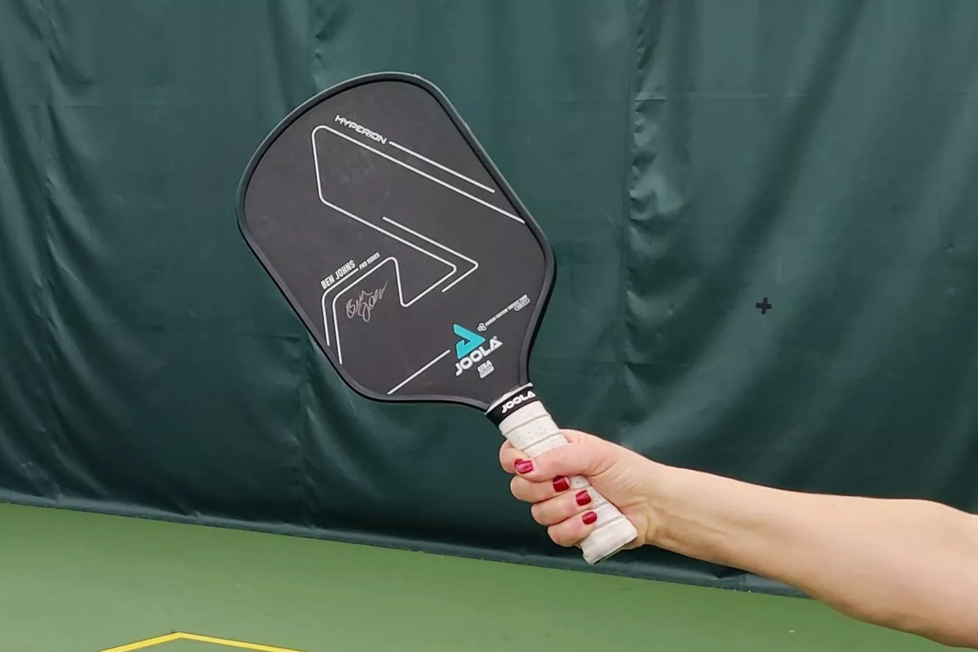 A person holds up the JOOLA Ben Johns Hyperion C2 CFS 14 Pickleball Paddle