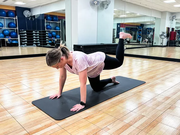 A person does kick backs on the Airex Pilates 190 Mat in an exercise studio