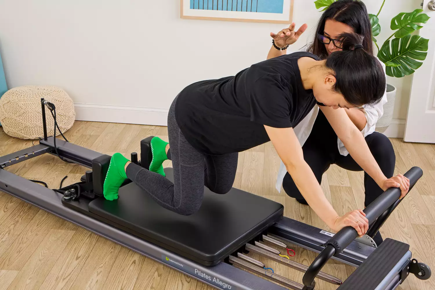 A person kneels on the Balanced Body Allegro Reformer