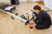 A person assembles the Merrithew At Home SPX Reformer Bundle