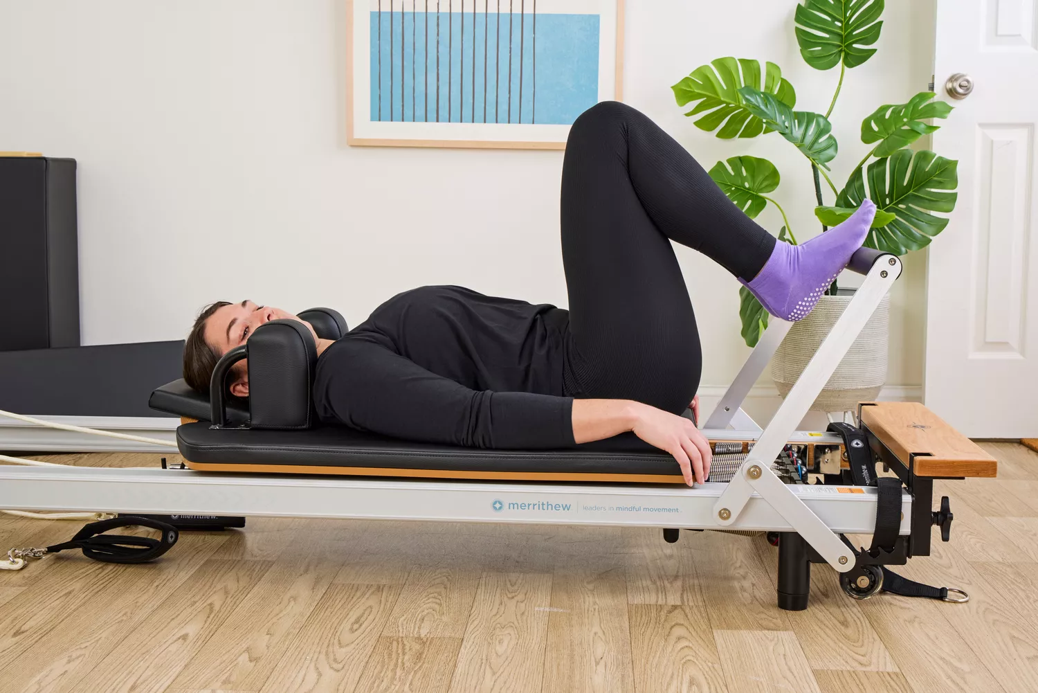 A person exercises using the Merrithew At Home SPX Reformer Bundle