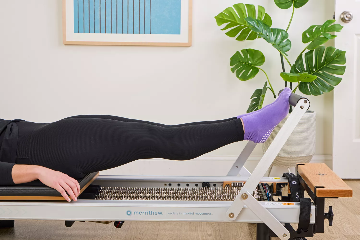 A person exercises using the Merrithew At Home SPX Reformer Bundle
