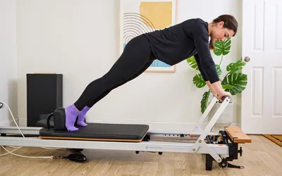 A person exercises using the Merrithew At Home SPX Reformer Bundle