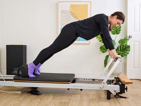 A person exercises using the Merrithew At Home SPX Reformer Bundle