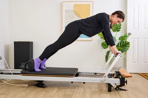 A person exercises using the Merrithew At Home SPX Reformer Bundle