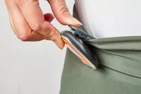 A person clips the PINGKO Outdoor Multi-Function Portable Sport Pedometer to their waistband