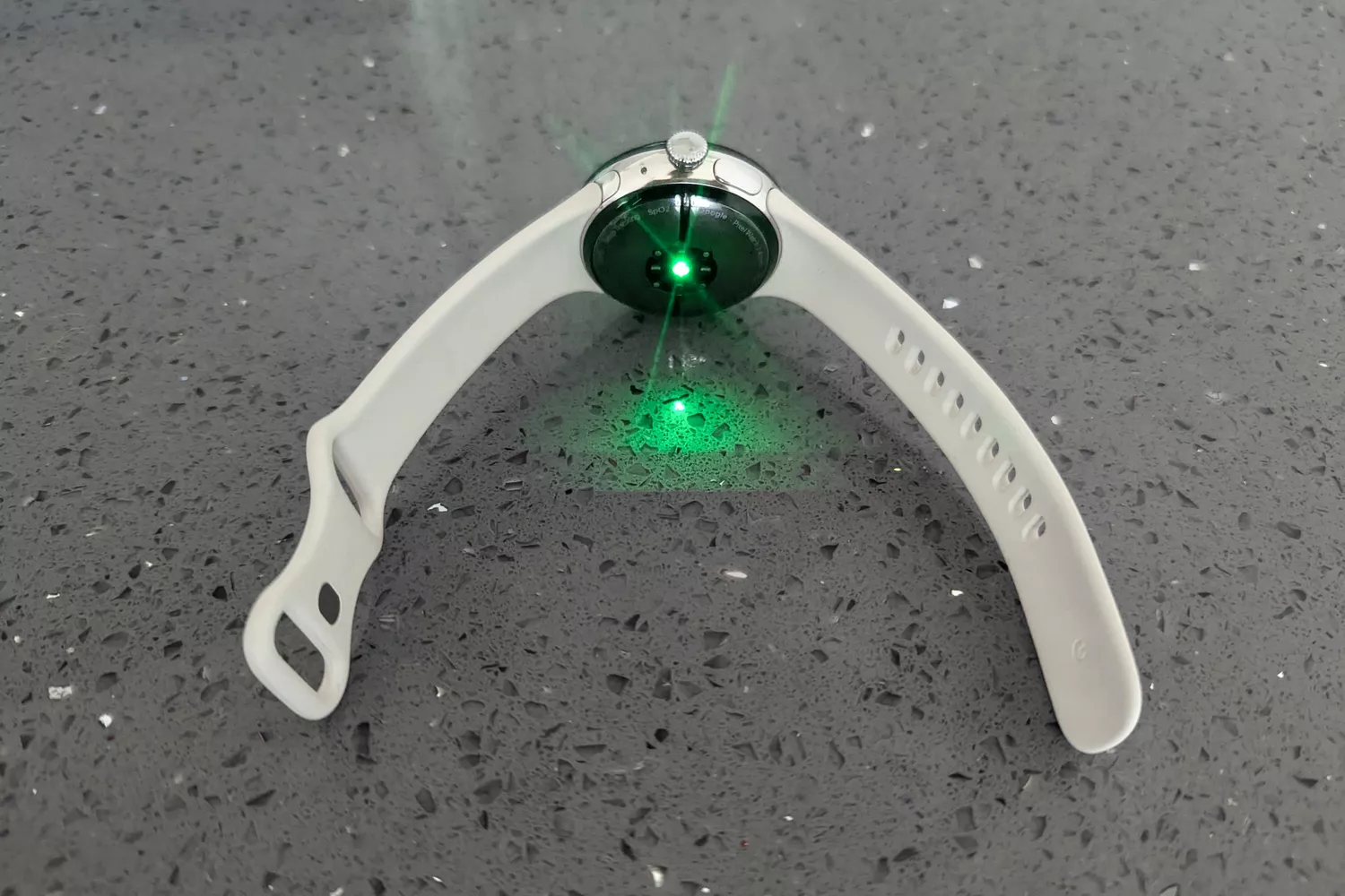 The Google Pixel Watch 3 with a green glowing light on the back of it