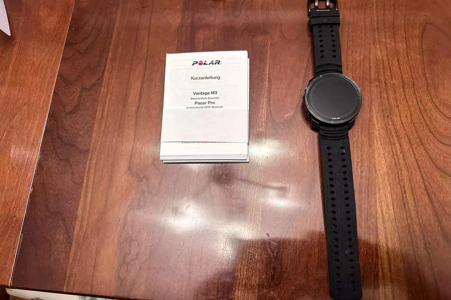 The Polar Vantage M3 Smart Multi-Sport Watch on a table next to the instruction manual