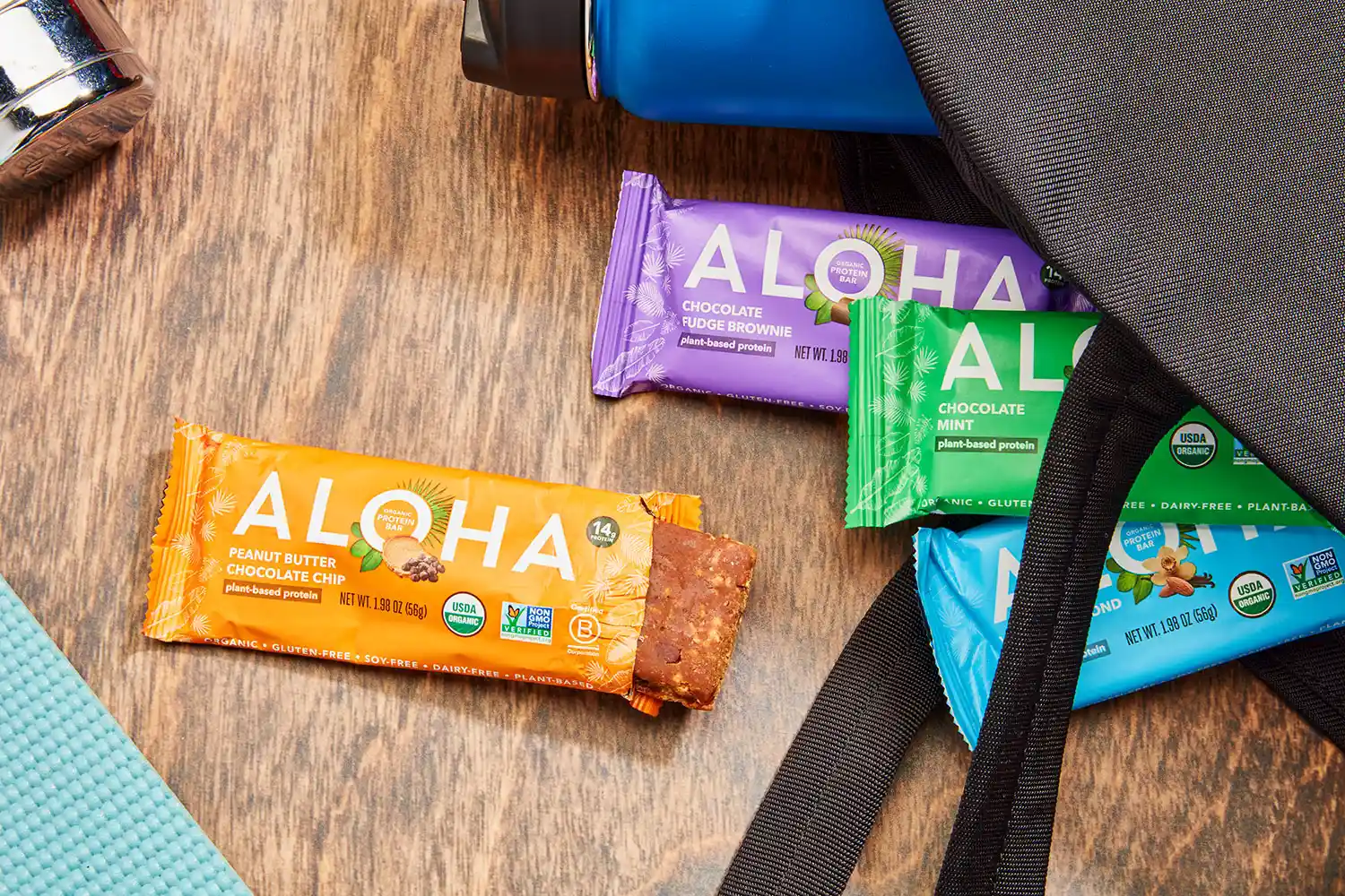 ALOHA Organic Plant-Based Protein Bars displayed with backpack and water bottle 