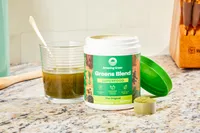 Amazing Grass Greens Blend Superfood mixed in a glass next to open container