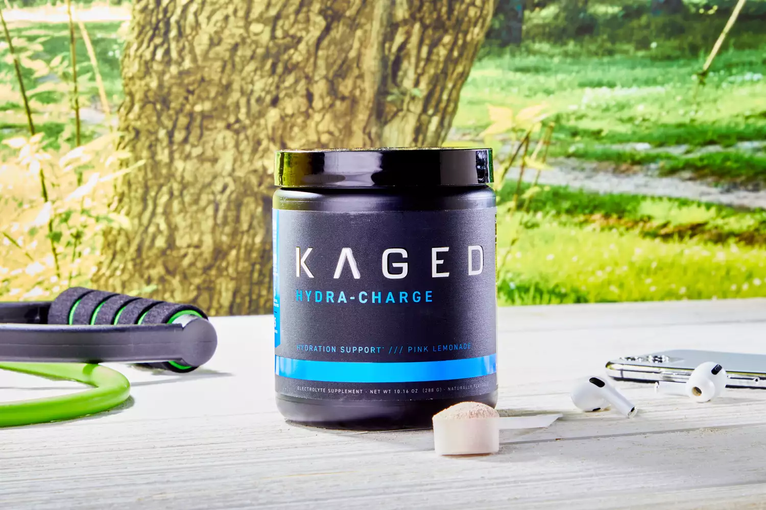 Kaged Hydra Charge in a scoop next to its packaging outside on a wooden table