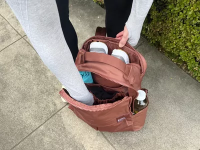 Close-up of a person with their hand inside an unzipped The North Face Women's Never Stop Utility Pack