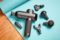 Renpho Power Massage Gun displayed with its accessories on an exercise mat