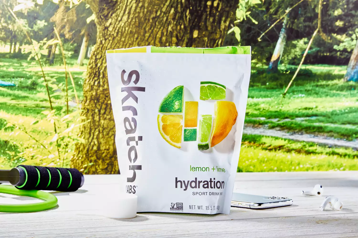 A package of Skratch Labs Sport Hydration Drink Mix next to its scoop on an outdoor table