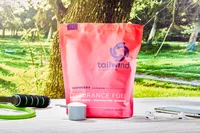 Tailwind Nutrition Caffeinated Endurance Fuel in a scoop next to the packaging on an outdoor table