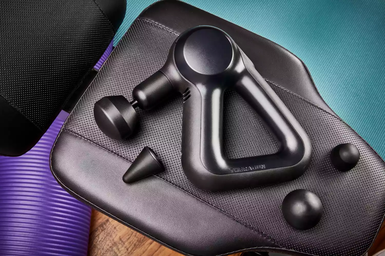 Therabody Theragun Prime (4th Generation) and attachment heads on a weight bench