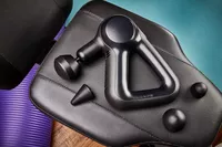 Therabody Theragun Prime (4th Generation) and attachment heads on a weight bench