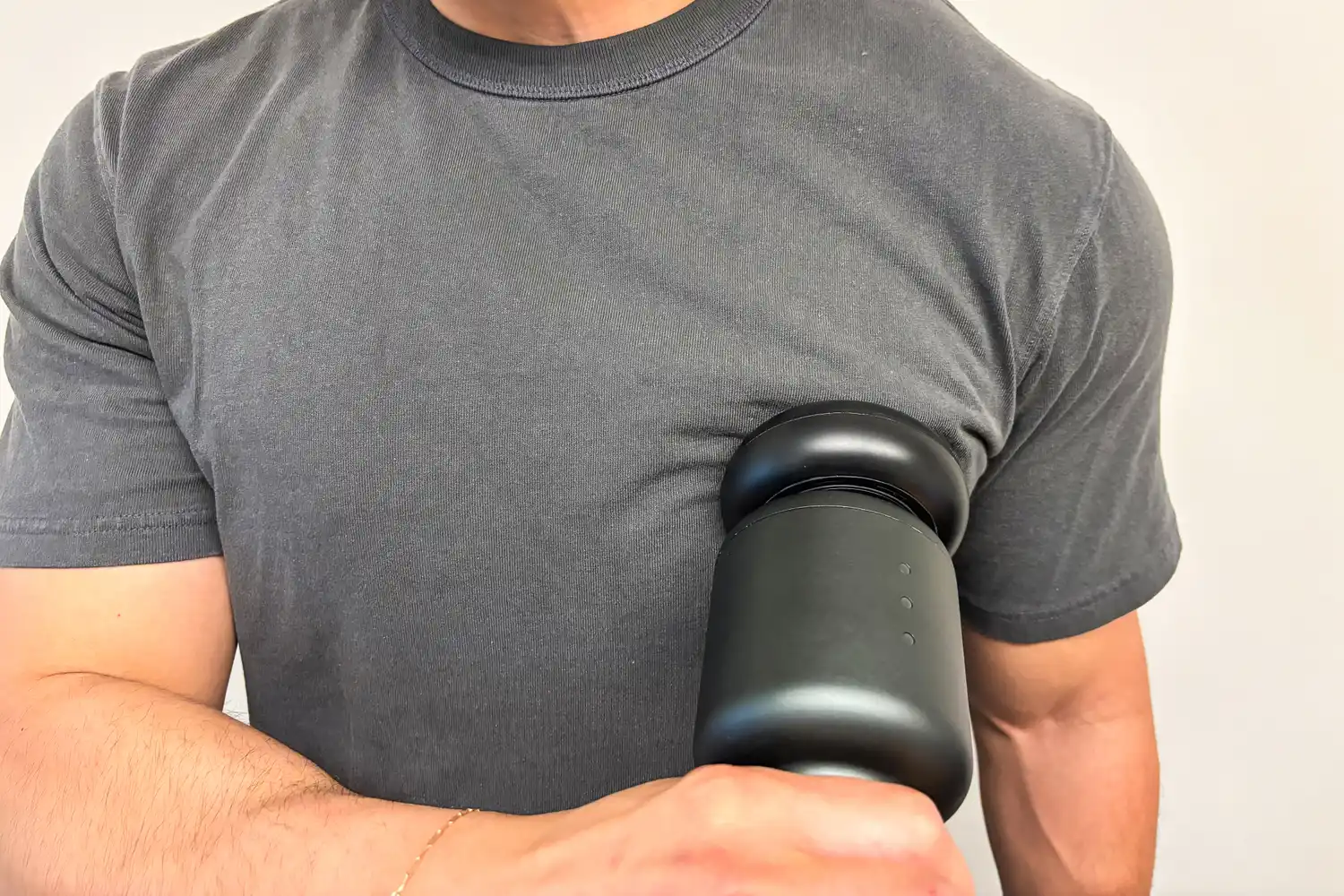 A person uses the Rally Massage Gun on their pectoral