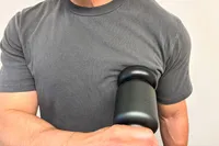 A person uses the Rally Massage Gun on their pectoral
