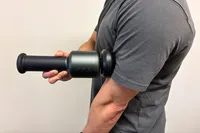 A person uses the Rally Massage Gun on their arm