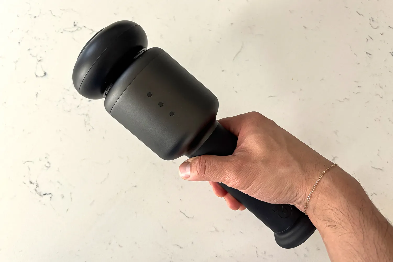 A person holds up the Rally Massage Gun