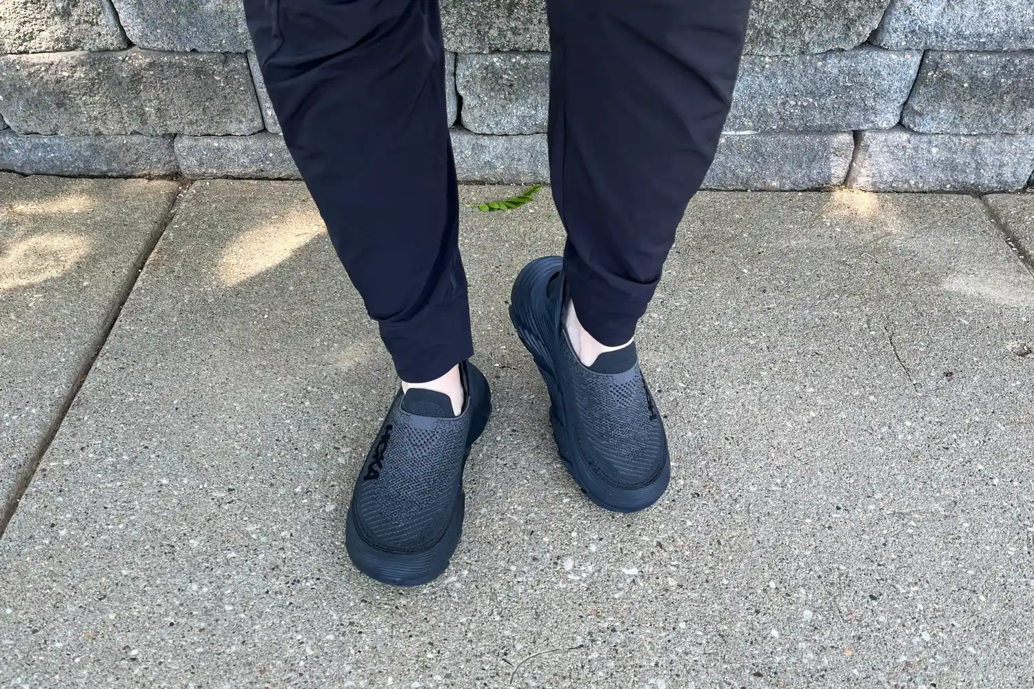 A person wearing the Hoka Restore TC Recovery Shoes on a sidewalk