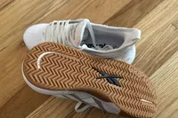The Reebok Nano Court sneakers posed to show the bottom of a shoe on wood
